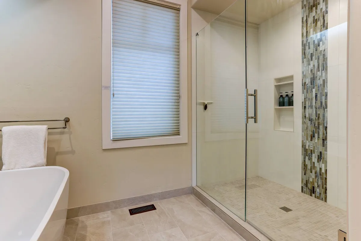 A modern bathroom featuring a freestanding bathtub and a glass-enclosed shower with a textured wall, offering a tranquil and spa-inspired atmosphere. The clean design and soft lighting create a space for true relaxation.