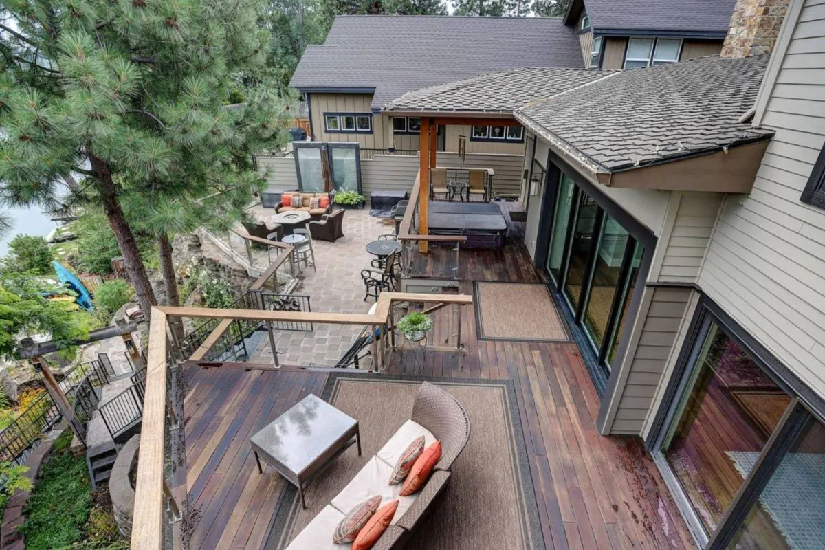 A spacious wooden deck with a bubbling hot tub overlooks lush landscaping and a tranquil garden. Comfortable outdoor seating areas invite conversation and relaxation, while the deck’s vantage point offers picturesque river views. The deck is surrounded by greenery and exudes a private, resort-like atmosphere.