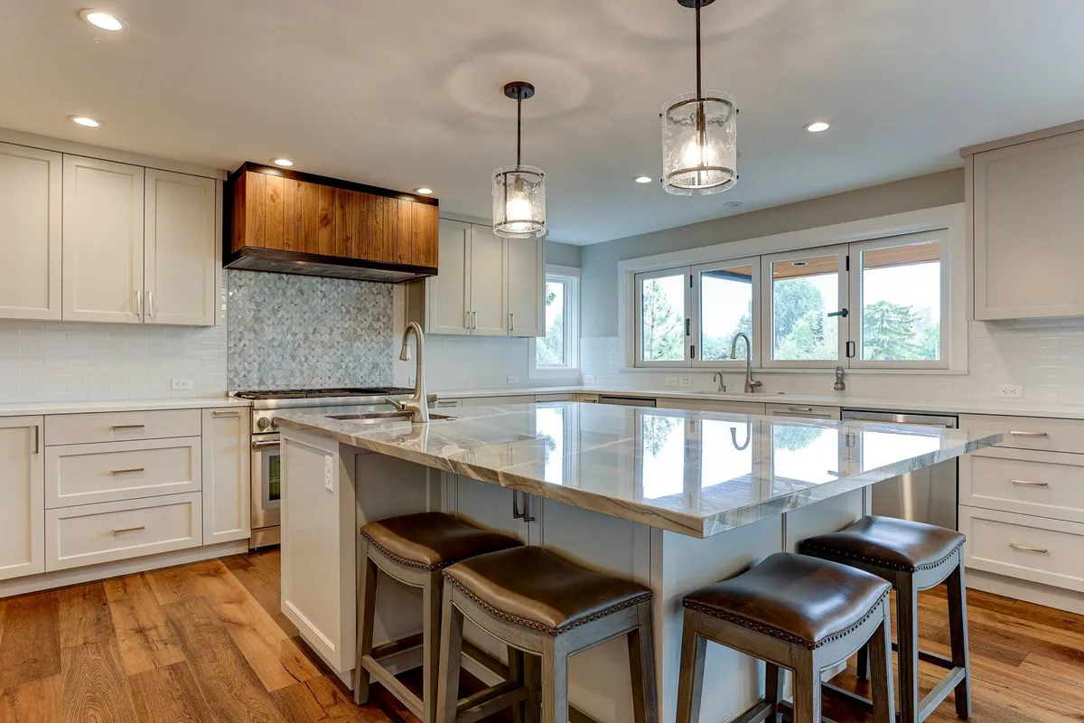 An elegant gourmet kitchen featuring a large kitchen island with pendant lights, stainless steel appliances, and warm wooden accents. The layout encourages conversation and socializing, while the ample counter space is perfect for preparing meals together. Natural light enhances the bright, open feeling of the space.