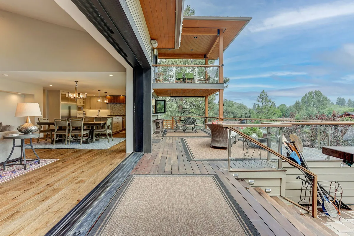 This exterior image showcases an open patio with a spacious dining area surrounded by natural greenery. The setting radiates a warm, inviting atmosphere, ideal for outdoor gatherings, meals, and relaxation. The scene encapsulates the feeling of celebrating or unwinding in nature, emphasizing both the group-friendly and multi-generational appeal of the estate.