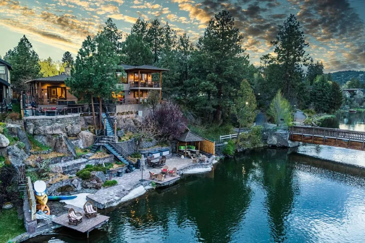 A spacious wooden deck overlooking the river, with comfortable seating, a fire pit, and views of the house, bridge, and surrounding landscape. The setting is inviting and highlights both the social and scenic aspects of the estate.